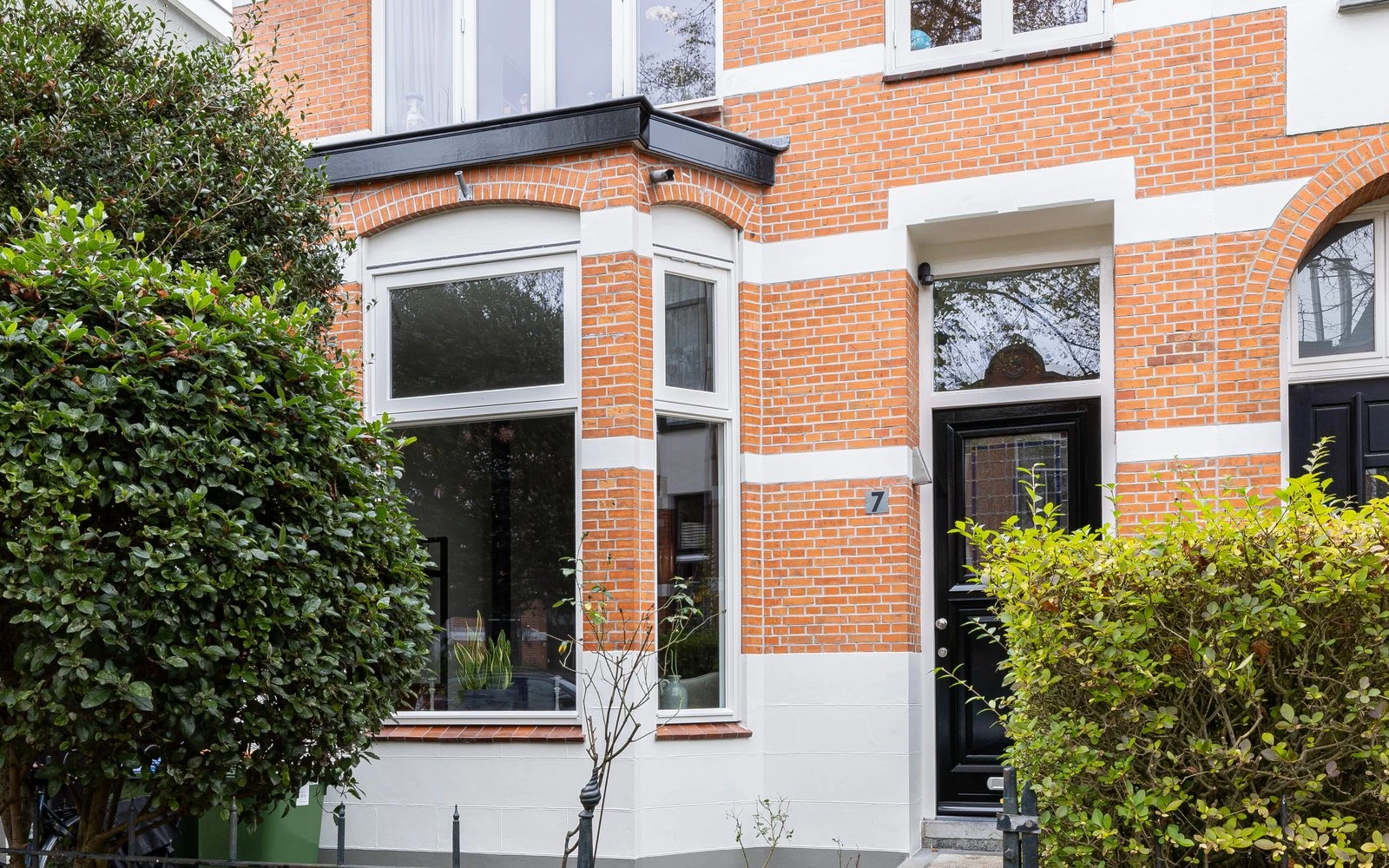 Bakstenen jaren-30 woning met erker, gezien vanaf de voortuin in het najaar