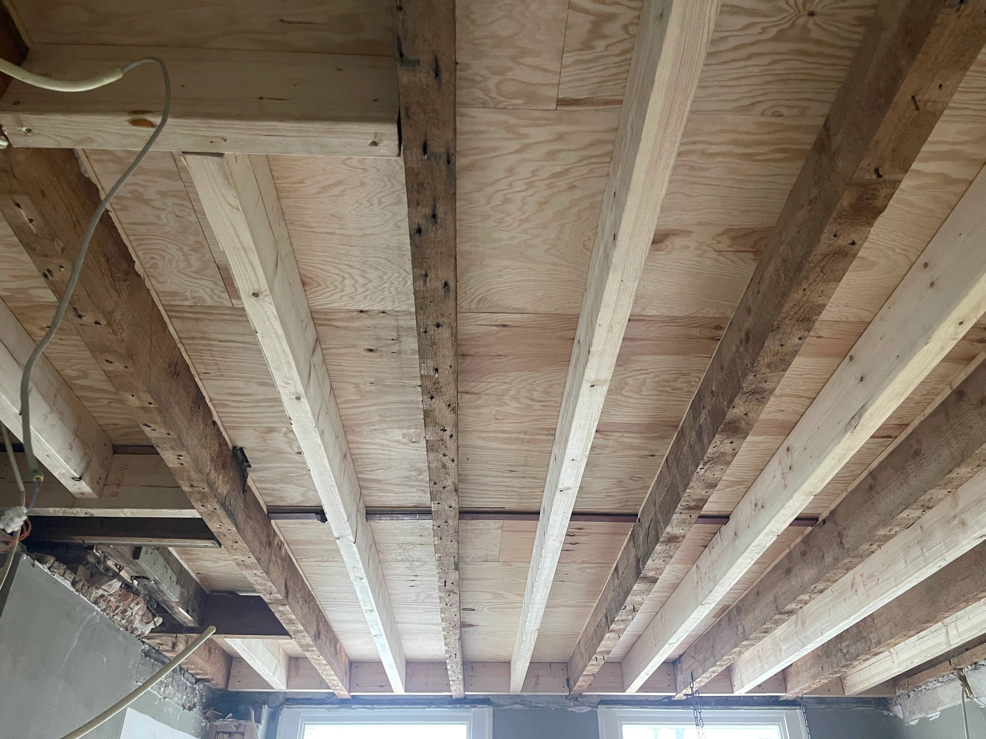 De verzwaarde vloerconstructie van onderaf, met nieuwe balken en een beplating van underlayment