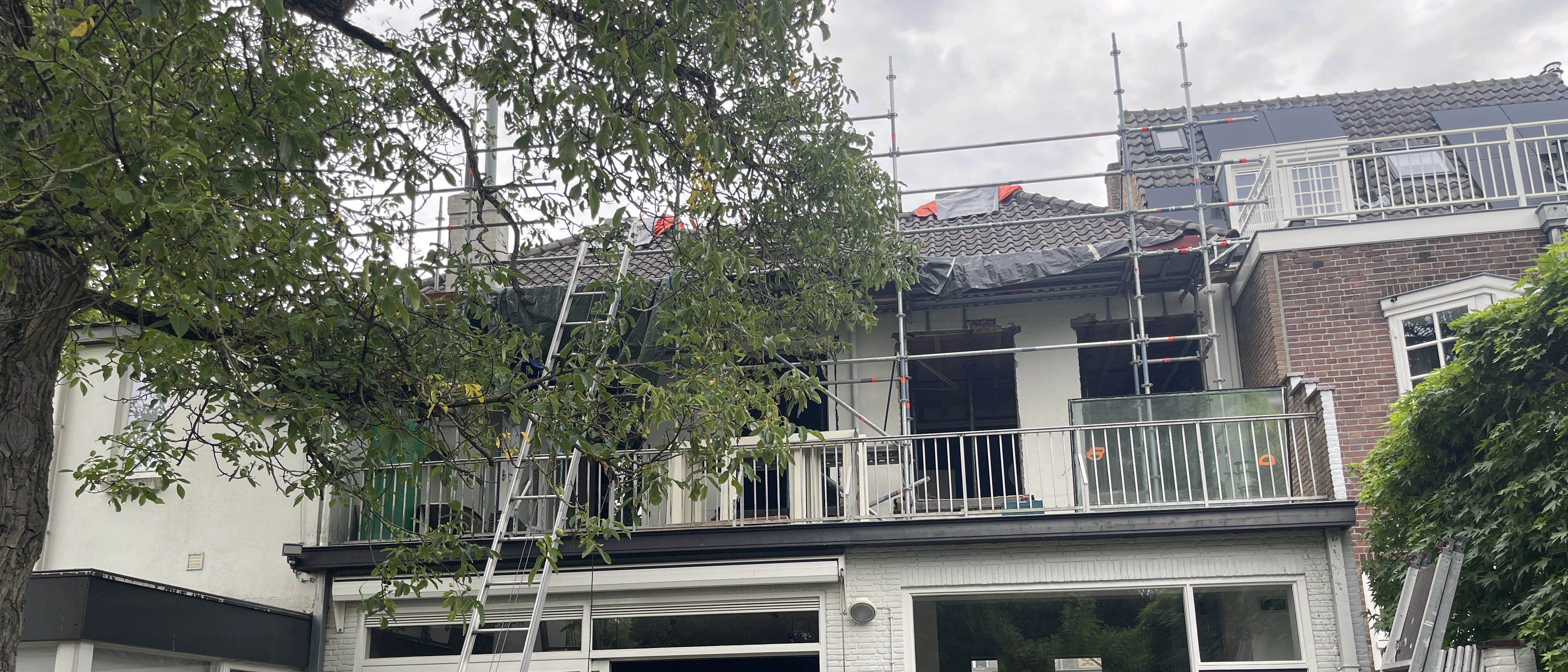 Achtergevel van de woning in de steigers, met open kozijnen en een dak dat is opengelegd