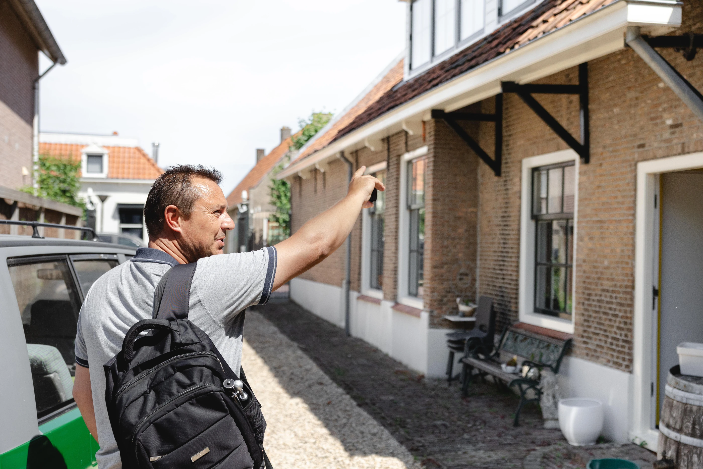 Bouwkundig inspecteur bekijkt de gevel van een oude woning in een smal straatje